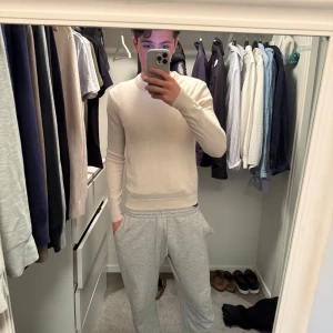 Beige stickad tröja These Glory Days - Snygg beige stickad tröja från These Glory Days i mjuk merinoull. Tröjan har rund hals, ribbade muddar och lång ärm. Perfekt för dig som gillar stilrena och enkla plagg med skön passform. Passar dig som vill ha en clean look.