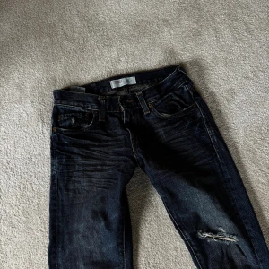 Levi's 511 mörkblå skinny jeans - Snygga Levi's 511 jeans i mörkblå tvätt med slitningar och trasiga detaljer vid knäna. Skinny fit och klassisk femficksdesign, med Levi's patch bak i midjan. Perfekta för dig som gillar en tuff och modern look.