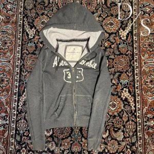 Vintage Abercrombie & fitch hoodie - Sjukt snygg vintage Abercrombie and fitch hoodie, dessa har blivit otroligt trendiga och eftertraktade senast, passa på innan den är såld! Mått Bredd:43cm Längd:59cm