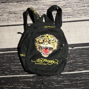 Ed Hardy ryggsäck - Tvär fet edhardy ryggsäck yao🤯🤯säljs då den inte kmr till användning. Bra skick utom att insidan har ett hål så facken sitter ihop, går antagligen o sy ihop eller fixa🙏✌️pm för intresse