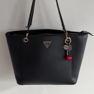 Guess handväska  - Superfin väska. Bredd: 31cm. Djup: 12. Höjd: 26cm. Slitna där banden fäster till axelbandet, annars fin och hel! Nypris 1800kr. 