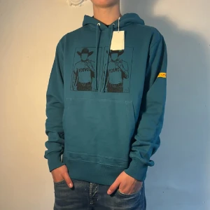 Blå hoodie Helmut Lang med cowboy-tryck - Säljer en blå hoodie från Helmut Lang. Riktigt snygg till hösten, kommer med tags!. Nypris ca: 4000 mitt pris: 999