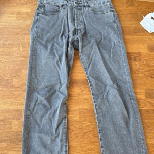Levi's 501 grå jeans W32 L30 - Klassiska Levi's 501 jeans i en snygg grå tvätt. Rak passform med fem fickor och knappgylf. Perfekta för dig som gillar en tidlös och avslappnad look. Ikonisk läderpatch bak i midjan och tydlig Levi's-röd etikett på bakfickan.