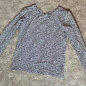 Leopardmönstrad långärmad topp från Lindex - Säljer en långärmad topp med svartvitt leopardmönster och snygg detalj med öppen rygg och korsade band. Jag har klippt bort lappen, men den är från Lindex i storlek 170. Kom gärna med prisförslag!