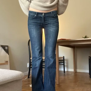 Bootcut jeans från 7 For All Mankind - Snygga blå bootcut jeans från 7 For All Mankind med låg midja. Små stenar på bakfickorna men har ramlar av lite se bilder. Innerbenslängd 83cm midjemått 39cm