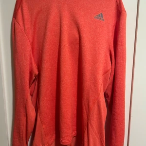 Röd långärmad tröja från Adidas XL - Säljer en röd långärmad tröja från Adidas i storlek XL. Tröjan har en enkel och sportig design med Adidas-logga på bröstet och är tillverkad i mjukt fleecematerial. Perfekt för träning eller chill dagar.