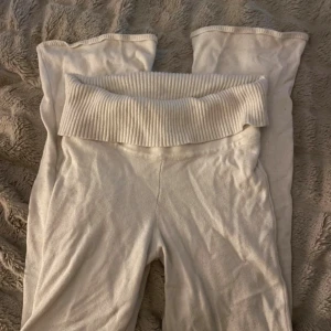 Vita ribbade mjukisbyxor med hög midja - Mysiga vita mjukisbyxor med bred ribbad midja som kan vikas ner. Byxorna är raka i modellen och har en mjuk och skön känsla, perfekta för chill dagar hemma. Materialet är stretchigt och bekvämt.