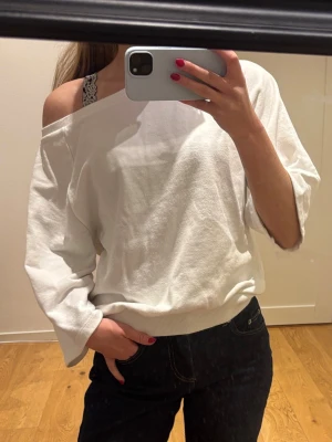 Vit offshoulder sweatshirt - Säljer en vit sweatshirt med offshoulder-design och avslappnad passform. Från Nelly strl xs. Pris 100 kr. 