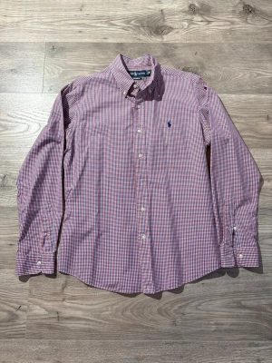 Ralph Lauren  - Klassisk rutig skjorta från Ralph Lauren i rött, blått och vitt. Skjortan har button-down krage, långa ärmar och broderad logga på bröstet. Tillverkad i mjuk bomull och har normal passform med knappar framtill.