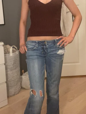 Blå bootcut jeans - Säljer ett par blå bootcut jeans med slitningar och hål på knät. Dom va skinny inanna så jag sydde dom till bootcut