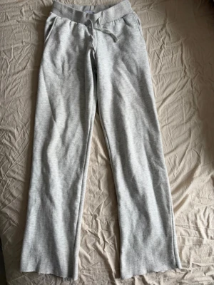 Ljusgrå mjukisbyxor XS - Ljusgrå mjukisbyxor från 157 i storlek XS. Byxorna har resår och snörning i midjan samt raka ben. Tillverkade i mjukt bomullsmaterial som är perfekt för chill dagar. Klassisk modell med fickor på sidorna och ribbad midja.