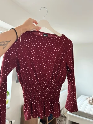 Vinröd prickig blus från Gina Tricot - Supersöt vinröd blus från Gina Tricot med vita prickar. Använd en gång, annars som ny