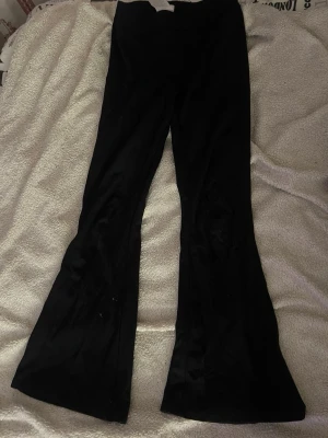 Svarta bootcut byxor - Säljer ett par svarta bootcut byxor med snygg utsvängd passform. Byxorna har en klassisk look och är perfekta för dig som gillar en trendig siluett. Materialet känns mjukt och stretchigt, vilket gör dem riktigt bekväma att bära.