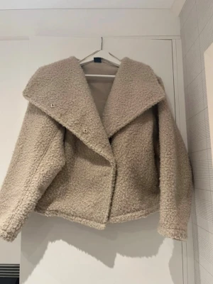 Beige teddyjacka med bred krage - Säljer en beige teddyjacka med bred, markerad krage och stora knappar framtill. Jackan har en mysig, fluffig struktur och är perfekt för kyliga dagar ❣️