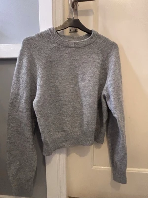 Grå stickad tröja - Mysig grå stickad tröja från h&m i storlek S. Tröjan har rund halsringning, ribbade muddar och lång ärm. Perfekt till lager på lager under höst och vinter. Enkel och stilren design som passar till allt.