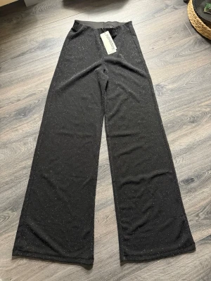 Glittriga svarta wide byxor Kappahl - Säljer ett par svarta byxor från Kappahl med glittriga detaljer.