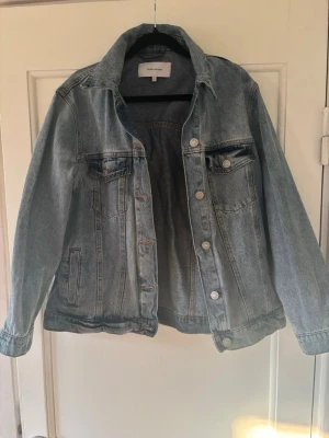 Blå jeansjacka från Bubbleroom - Klassisk blå jeansjacka från Bubbleroom med silverfärgade knappar och två bröstfickor med lock. Jackan har en rak passform och långa ärmar. Perfekt att slänga över en hoodie eller t-shirt för en chill look.