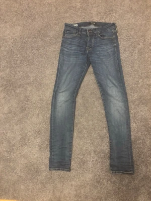 Jack and Jones Slim Glenn blå jeans 29/32 - Snygga blå jeans från Jack and Jones Slim Glenn i storlek 29/32. Modellen har en slim passform med och klassisk femficksdesign. Jeansen har en lätt tvättad look och är tillverkade i mjukt denimtyg.