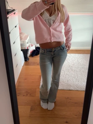 Ljusrosa  kofta med knappar - Supersöt ljusrosa kofta  passform och v-ringad hals. Tröjan har långa ärmar och stängs med två knappar framtill. Perfekt för dig som gillar en mjuk och feminin stil. Passar till både jeans och kjol.