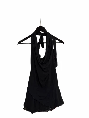 Svart omlott halterneck klänning - Säljer en svart klänning  med halterneck och omlott-detalj. Toppen har en draperad framsida och knyt i nacken. Den är även öppen vid ryggen
