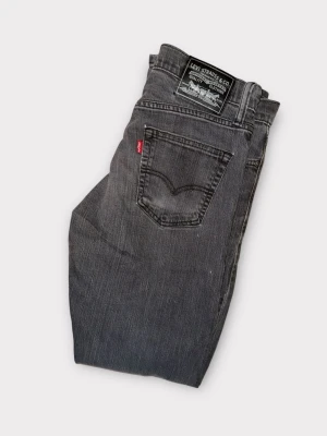 Levi's 514 svarta jeans straight fit - Svarta Levi's 514 jeans med klassisk straight fit och fem fickor. Snyggt slitna detaljer och ikonisk röd Levi's-tag på bakfickan. Jeansen har normal passform och är tillverkade i robust denim för en cool och tidlös look.