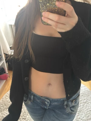 Svart ribbat linne  - Säljer ett svart linne från H&M i ribbad stretchig kvalitet. Toppen är croppad, perfekt till jeans eller kjol. Enkel och stilren design som är lätt att matcha med olika outfits!💗