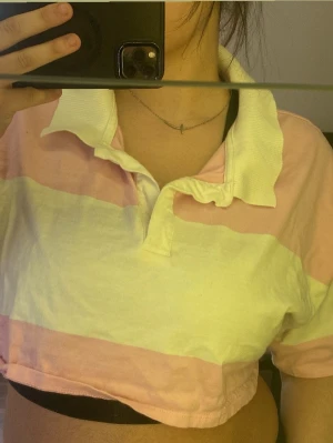  Croppad T-shirt - Säljer en croppad t-shirt från FB sisters i storlek XL. T-shirten har breda rosa och vita ränder, krage och korta ärmar.