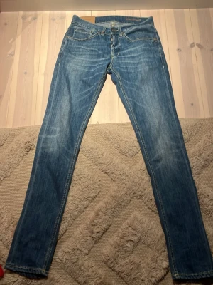 Dondup jeans  - Säljer ett par dondup jeans i blå tvätt. De har en slim passform med raka ben och fem fickor. Jeansen är tillverkade i bomull och har snygga slitningar för en avslappnad look. Perfekta till vardags och passar till det mesta. Dem är i storlek 30 och är köpta för 3 år sedan. Säljer jeansen för att jag växt ut dem skriv om ni har några frågor 
