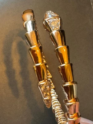 Guldigt armband  - Snyggt armband i guldtonat metall med geometriska, segmenterade länkar och glittrande kristalldetaljer på ändarna. Armbandet har en modern och edgy design som sticker ut och passar perfekt för dig som gillar statement-smycken.