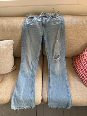 Ljusblå bootcut jeans från Gina Tricot - Snygga ljusblå bootcut jeans från Gina Tricot med slitna detaljer. 