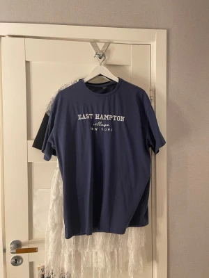 Blå East Hampton t-shirt - Snygg blå t-shirt från East Hampton med vit text på bröstet där det står 'East Hampton village New York'. Klassisk rund halsringning och korta ärmar.
