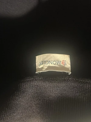 Mörkblå dunväst från Moncler - Snygg mörkblå dunväst från Moncler med klassisk quiltad design och Moncler-logga på bröstet. Västen har en stilren look och är perfekt för lager-på-lager. Materialet är glansigt och fyllningen ger bra värme. Passar dig som vill ha något både trendigt och funktionellt.