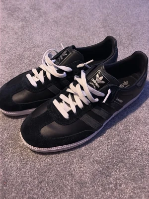  Adidas Samba ”LIMITED EDITION” svarta  - Klassiska svarta Adidas Samba sneakers med vita snören och detaljer i mocka och skinn. Ikoniska tre ränder på sidan och vit yttersula. Perfekta för dig som gillar retrostil och streetwear. PRIS KAN DISKUTERAS!!!!