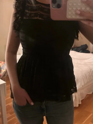 Svart spetslinne med volangdetaljer - Detta är nog en av mina absolut bästa köp någonsin, men behöver tyvärr sälja nu för att den börjar bli för liten! Super fin till middagar, behövs igentligen ingen bh i, öppen rygg, storlek xs-s. Lappen är bort riven så vet tyvärr inte märket