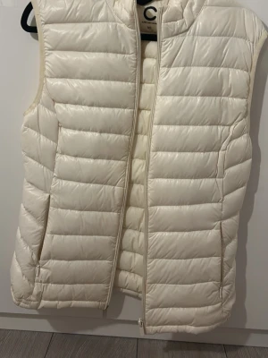 Väst från Cubus  - Snygg off white dunväst från Super Light Down i storlek XS. Västen är quiltad med horisontella sömmar, har dragkedja framtill och två fickor med dragkedja. Perfekt att slänga över en hoodie eller tröja för extra värme.
