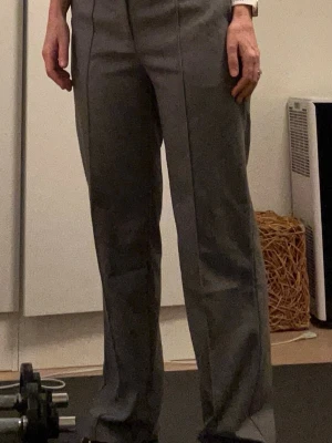 Gråa kostymbyxor från Bik Bok 40 - Säljer ett par stilrena gråa kostymbyxor från Bik Bok i storlek 40. Byxorna är medelmidjade med raka ben och har pressveck framtill. Klassisk look med hällor för bälte och diskreta fickor bak. Perfekta till en snygg topp eller skjorta. Nya med prislappar kvar, nypris 599