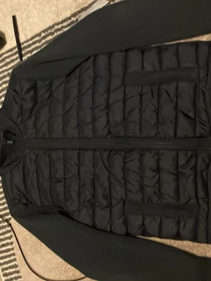 Mörkblå dunväst med dragkedja - Snygg mörkblå dunväst med quiltat mönster och hel dragkedja framtill. Västen har hög krage och två diskreta sidofickor. Perfekt för lager-på-lager och ger en clean look till din outfit.