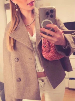 Beige kappa med dubbelknäppning - Stilren beige kappa med bred krage och dubbelknäppning framtill. Modellen är loose fit och har långa ärmar. Perfekt för höst och vinter🍁💕