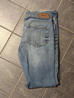 Blå raka jeans från Acne Studios - Säljer ett par klassiska blå jeans från Acne Studios med raka ben och normal passform. Ljus tvätt och subtila slitningar vid benslut. Perfekta till sneakers eller boots och tillverkade i mjukt bomullsjeans.