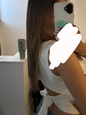 Vit ärmlös linnetopp med spets - Säljer en söt vit linnetopp med spetskant upptill och knyt i ryggen. Toppen är ärmlös och har en figurnära passform som framhäver midjan. Perfekt att matcha med jeans eller kjol för en fräsch look.