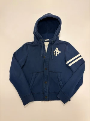 Abercrombie & fitch kofta - Blå vintage Abercrombie & Fitch kofta //  Mycket bra skick //  Storlek XXL men passar som en vanlig L // modellen på bilderna är 186cm 75kg //  Mått  Längd 68cm  Axelbredd 46cm  Bredd under armhålorna 59cm  Armlängd 75cm  Skriv vid minsta fråga eller fundering🤝