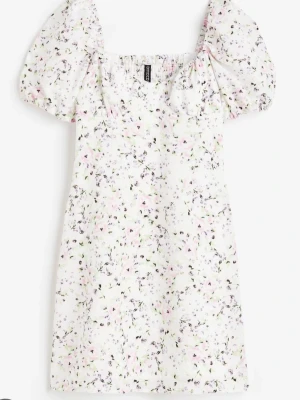 Vit blommig kortklänning H&M - Vit kortklänning från H&M med puffärmar och blommigt mönster i ljusa pastellfärger. 