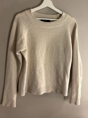 Beige stickad tröja från Weekday - Mysig beige stickad tröja från Weekday med rund halsringning och ribbade muddar vid ärmslut och nederkant. Tröjan har en enkel och stilren design, perfekt för lager-på-lager och passar till många olika outfits.