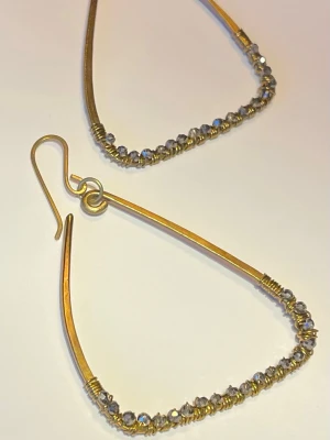 Handgjorda Triangulära örhängen med pärlor - Unika triangelformade örhängen i guldfärgad stål /mässing med små glittrande pärlor längs nederkanten. Örhängena har en modern och stilren design med krokfäste. Perfekta för dig som vill ha något annorlunda och trendigt.