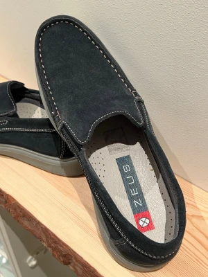Marinblåa mocka skor från Zeus - Stilrena svarta loafers från Zeus i mjuk mocka med kontrastsömmar och grå sula. Skorna har en klassisk slip-on design och perforerad innersula för extra komfort. Perfekta för dig som gillar en avslappnad men snygg look.