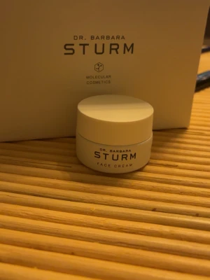 Dr. Barbara Sturm Face Cream 15 ml - Lyxig ansiktskräm från Dr. Barbara Sturm i en liten vit rund burk på 15 ml. Krämen är en del av Molecular Cosmetics-serien och passar perfekt för dig som vill ha återfuktad och fräsch hud. Snygg minimalistisk design och smidig storlek för necessären.