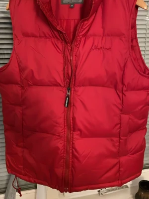 Röd dunväst från Northbrook - Snygg röd dunväst från Northbrook med hög krage och dragkedja framtill.