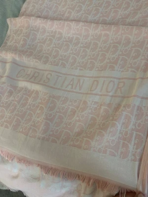 Ljusrosa halsduk från Christian Dior - Säljer en lyxig ljusrosa halsduk från Christian Dior med ikoniskt mönster och tydlig logga. Halsduken har fransade kanter och är tillverkad i ett mjukt, tunt tyg som känns exklusivt och trendigt. Perfekt accessoar för att lyfta din outfit. PRIS KAN DUSKUTERAS