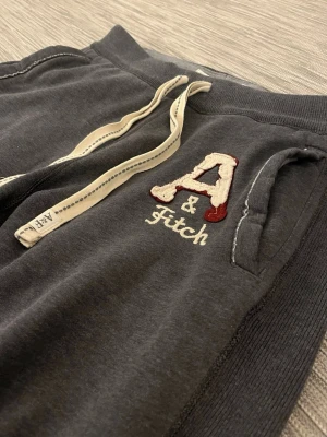 Mörkgrå mjukisbyxor från Abercrombie - Säljer dessa sällsynta A&F mjukisbyxor. De har använts sparsamt och har inga hål eller skador (utöver designen & lite heeldrag). De har en ”loose” passform och är väldigt varma trots att de inte är särskilt tjocka.  Storlek: XS passar som M/L Mått:  Midja: 45 cm (oknutna) Längd: 104 cm Ankelvidd: 27 cm  Hör av dig vid frågor eller funderingar!
