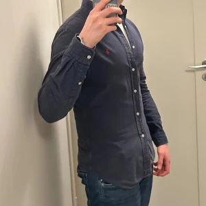 Ralph Lauren Skjorta - Säljer en riktigt fet Ralph Lauren Skjorta i marinblå färg. Storlek slim fit S. Skjortan är lite urtvättad så färgen har blivit lite ljusare. Snabb affär bättre pris. Om du har några funderingar så är det bara att fråga på! ❇️